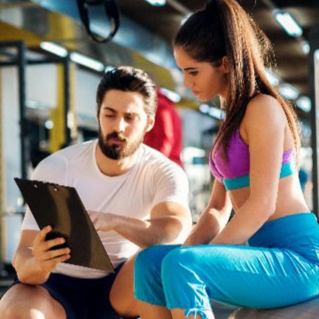 Personal trainer coaching client with customized workout plan at Team Dee’s fitness training studio.